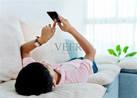 坐在客厅里玩手机的年轻人高清图片下载-正版图片500759172-摄图网