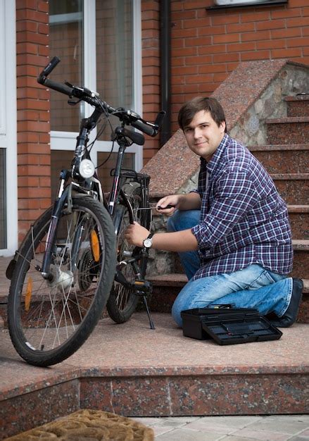 Premium Photo | Young man repairing bicycle on porch of his house