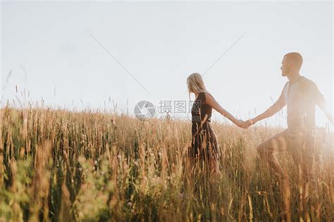 浪漫的男人和女友在阳光长草田里握着手行走高清图片下载-正版图片501890114-摄图网