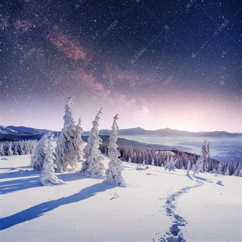 在冬雪的夜空中繁星闪烁。梦幻般的银河在除夕夜。冬天路在山里高清摄影大图-千库网