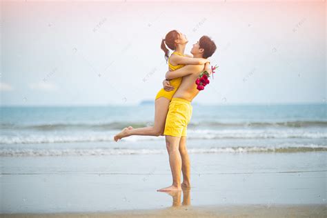 爱情白天一对年轻情侣沙滩拥抱转圈圈摄影图配图高清摄影大图-千库网