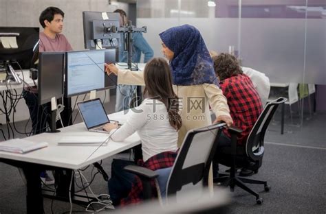 年轻的多民族商业软件开发人员团队在现代创业办公室编写编程代码时使用笔记本电脑一起工作高清摄影大图-千库网