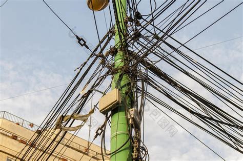 电线杆上的电线混乱的电线巢在极点和蓝天背-包图企业站