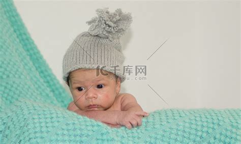 4 周大的新生男婴，绿色毯子上戴着灰色帽子高清摄影大图-千库网