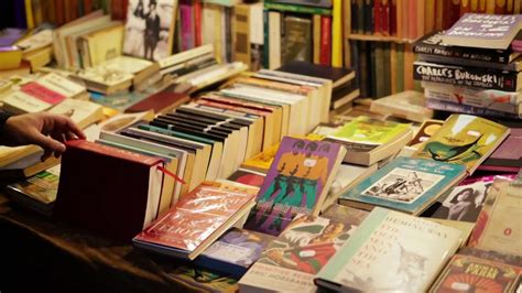 一个年轻人在二手书店里看旧书，在波多贝罗路跳蚤市场的一个市场摊位上出售的旧书视频素材_ID:VCG42N1356260599-VCG.COM