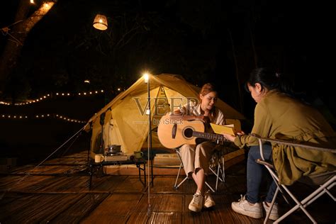 两个亚洲女性朋友在露营地一起唱着歌弹着吉他照片摄影图片_ID:424386550-Veer图库