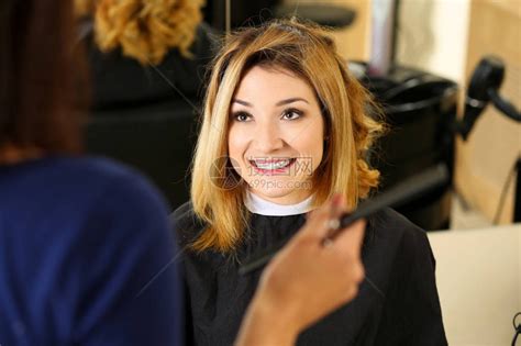 女理发师手拿着梳子为漂亮微笑的金发访客挑选新发型高清图片下载-正版图片507341871-摄图网