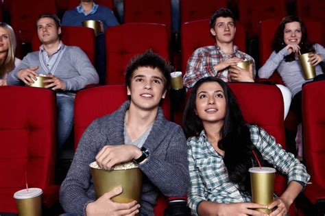 年轻人正在电影院里看电影图片-拿着爆米花和饮料看电影的年轻人素材-高清图片-摄影照片-寻图免费打包下载