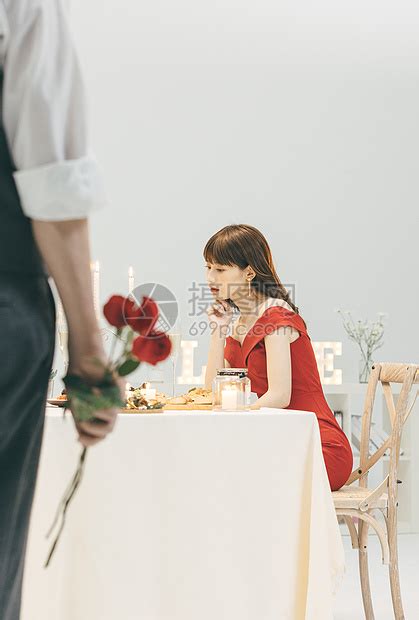 餐桌上等待的女生和手拿玫瑰的男生高清图片下载-正版图片501745512-摄图网